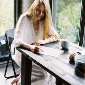 smiling barefooted lady writing thoughts on paper at home